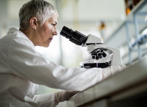 Female scientist analysing atoms through a microscope